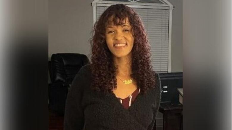 A woman in a black sweater with red curly hair