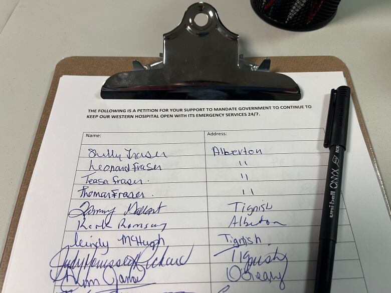 Names are written on a petition, with a pen on top of the paper. 