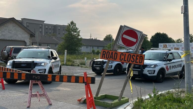 Three police cruisers behind a sign that says 