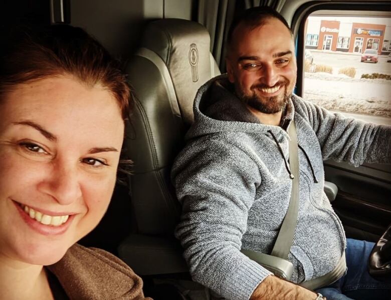 A selfie of a woman and a man sat in the cab of a truck