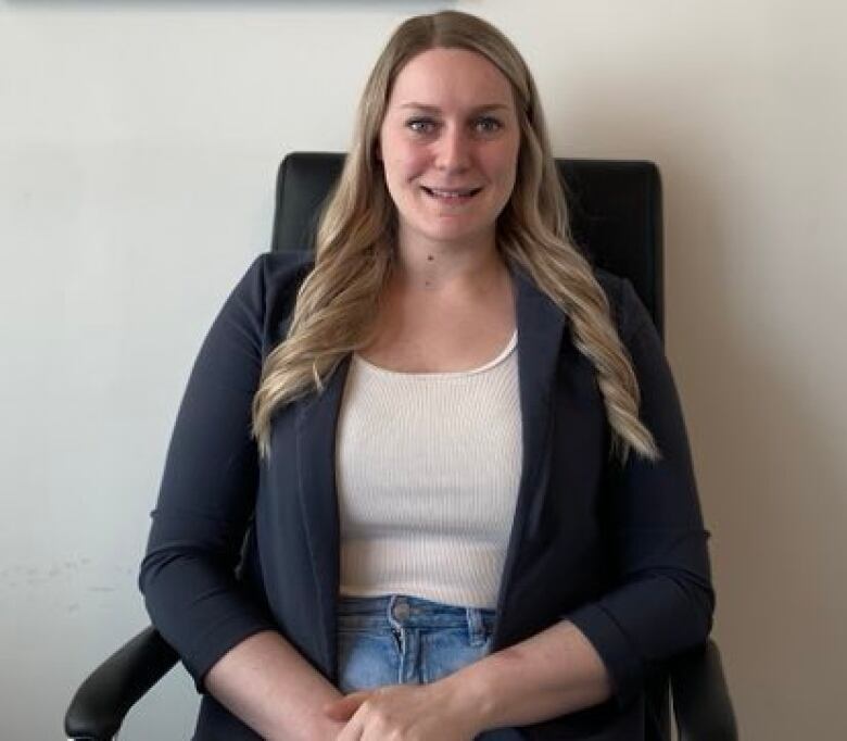 A woman sitting in a chair smiles at the camera.