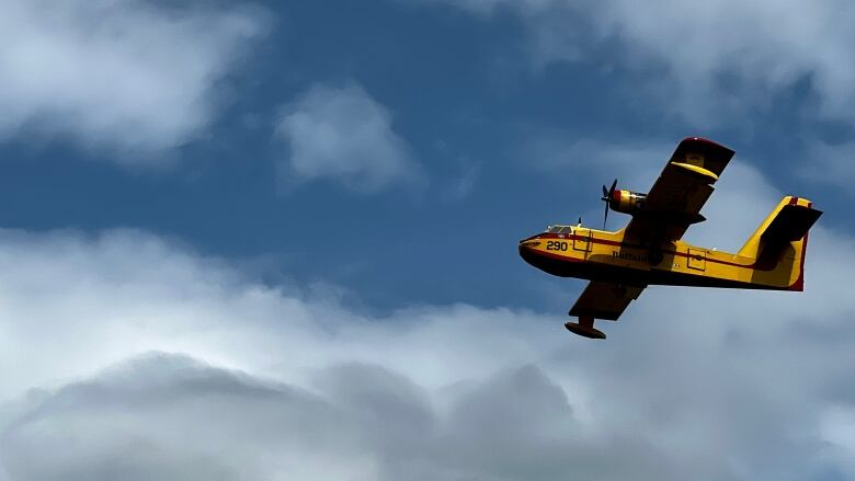 Yellow-and-red water bomber against blue sky.