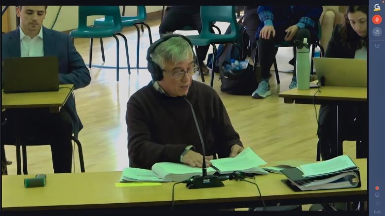 A man wearing headphones speaks into a microphone at a hearing.