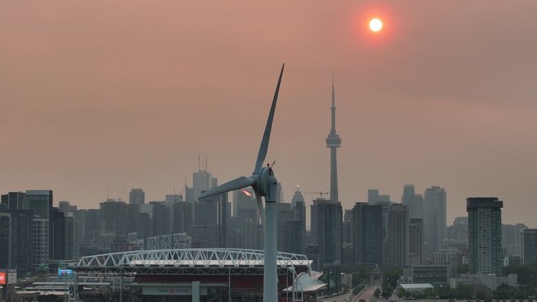 Smog and soot lingers over Toronto at sunrise due to smoke from forest fires.