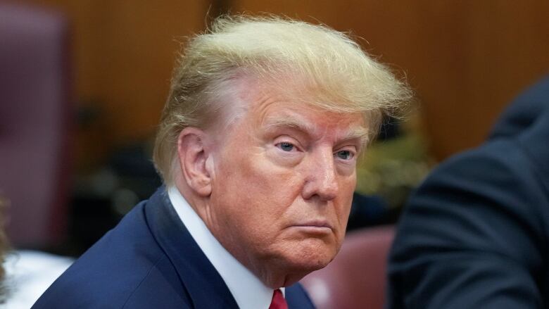 A man in a suit is seen in closeup sitting down.