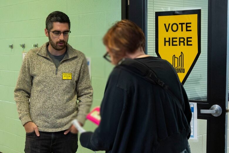 Man in a brown sweater waits at an advance poll in Toronto.