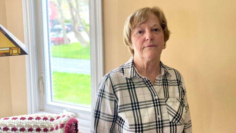 A woman in her living room looks at the camera.