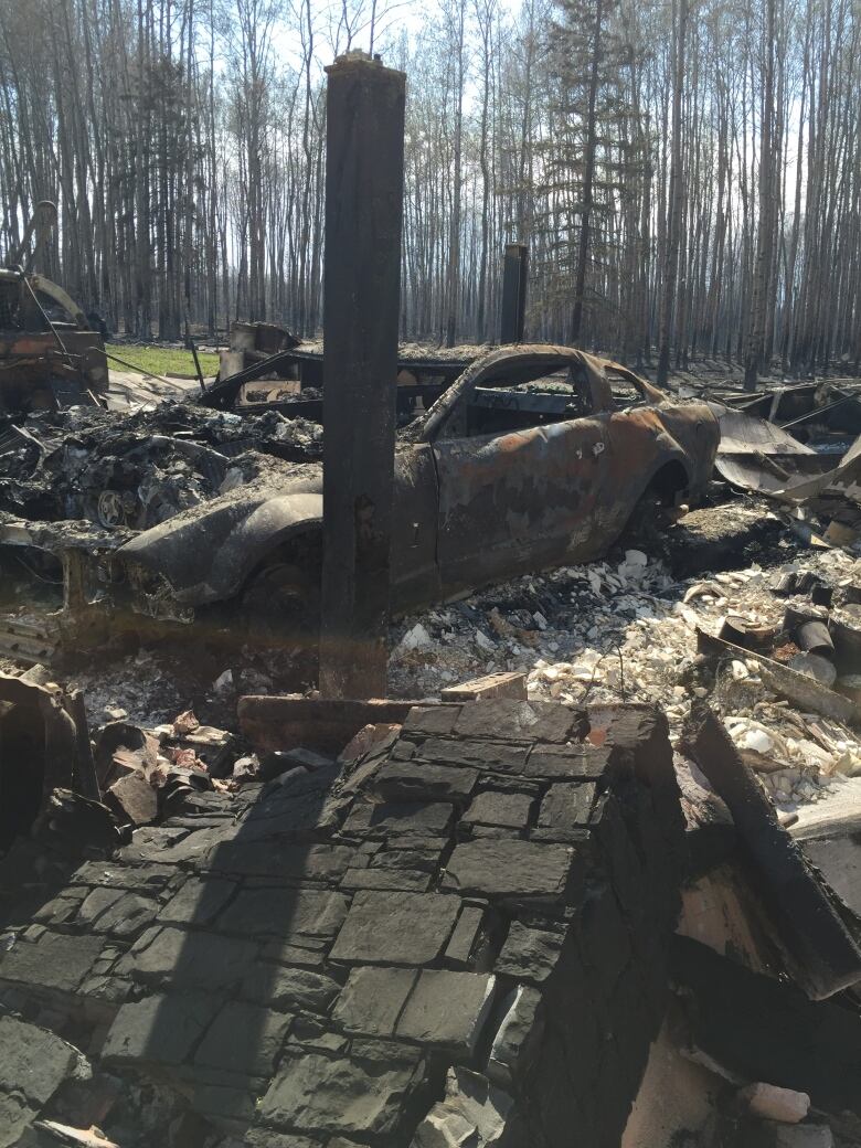 A burned out car is shown amid a pile of rubble in Fort McMurray in 2016.