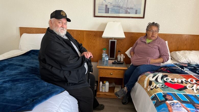 two people sitting on beds 