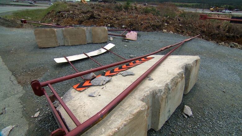 A concrete barrier and metal gate in pieces on the ground. 