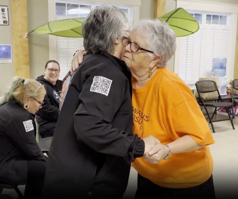 Two women embrace in a hug.