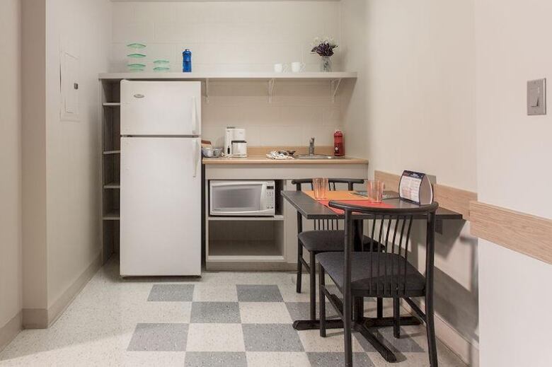 A small room with a two-person table to the right and a small counterspace with a microwave and fridge on the back wall.