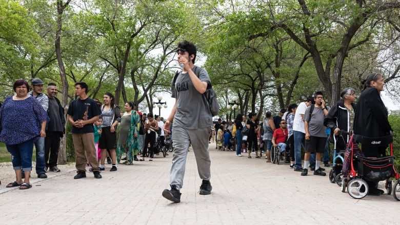 A man is pictured walking in between two long lineups of people.