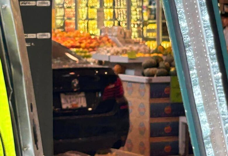 A closeup of a black car inside a produce section of a grocery store.