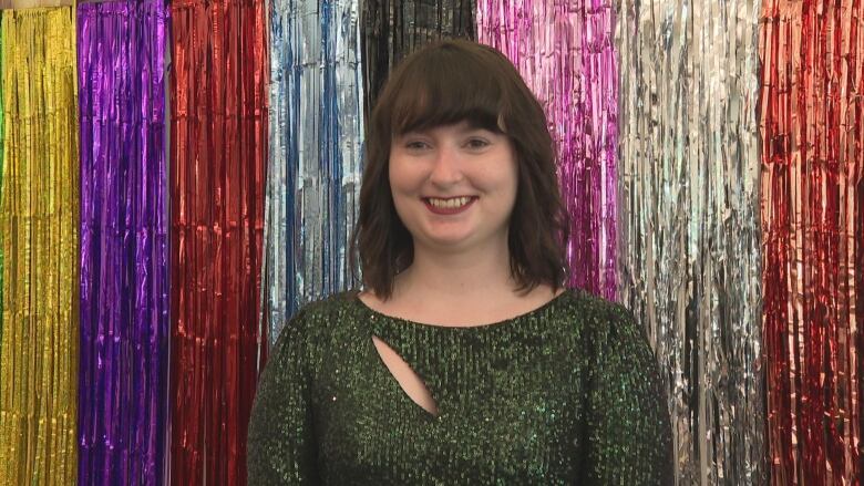 A woman stands in front of a sparkly backdrop. 