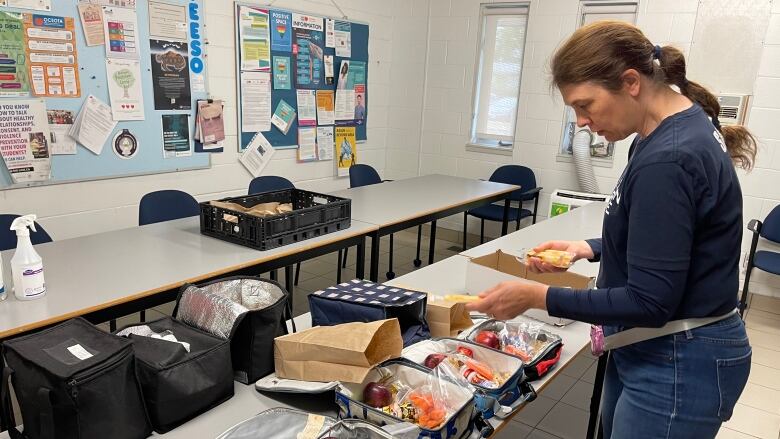 A woman prepares lunch boxes full of food.