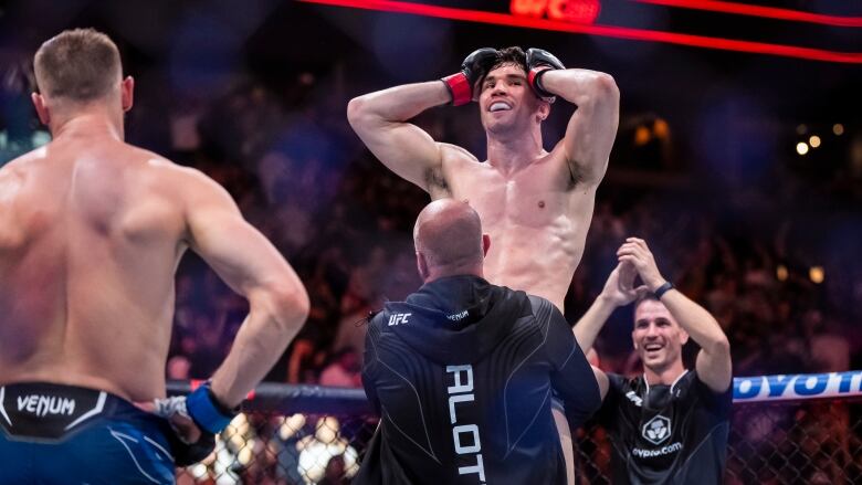 An MMA fighter holds his hands to his head in the middle of the octagon of a packed arena.