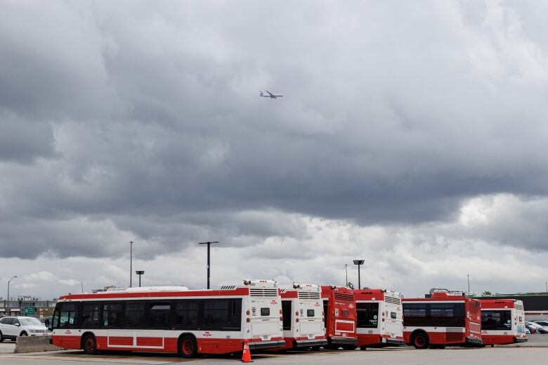 Deputy Prime Minister Chrystia Freeland joins deputy mayor of Toronto Jennifer McKelvie at an electric bus announcement, at a TTC yard in  North York, on April 24, 2023. See parked TTC buses under cloudy sky with passing plane.