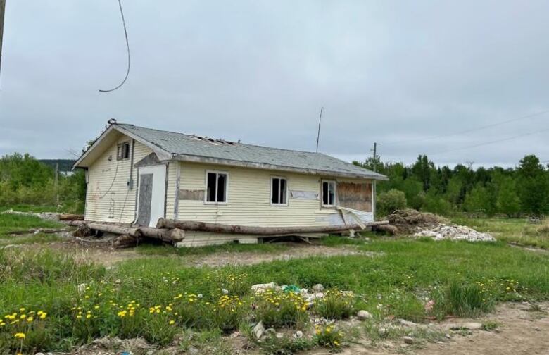 A home in deteriorating condition that is painted yellow. 