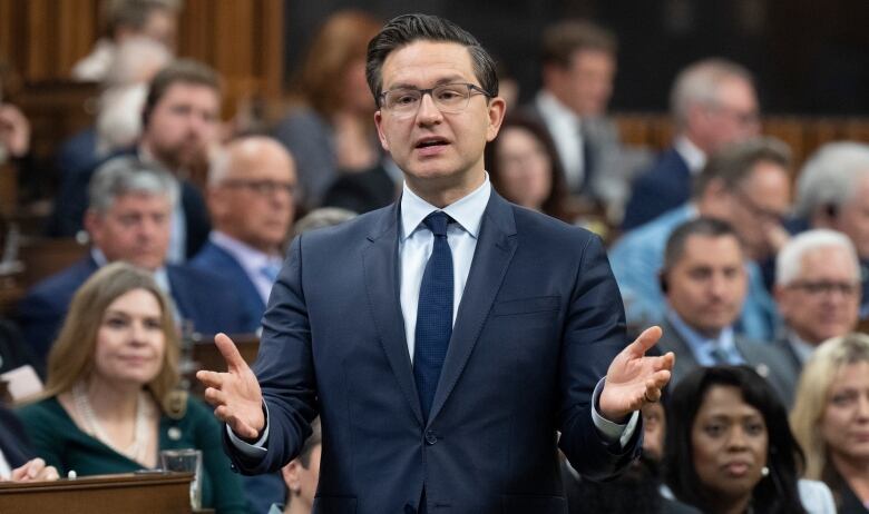 A man in a blue suit stands in the House of Commons.