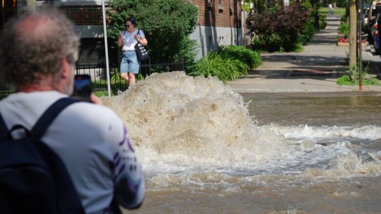 A man takes a picture of a flooded street in Montreal. 