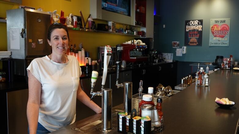 A diner owner poses behind a bar.