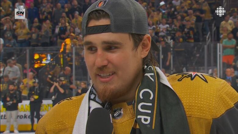 A headshot of a hockey player with a microphone in front of him.