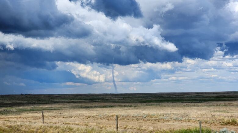 A tornado is visible in a sky that's filled with clouds.