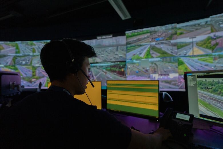 Man sitting at desk looking at monitors with a bunch of traffic video feeds.