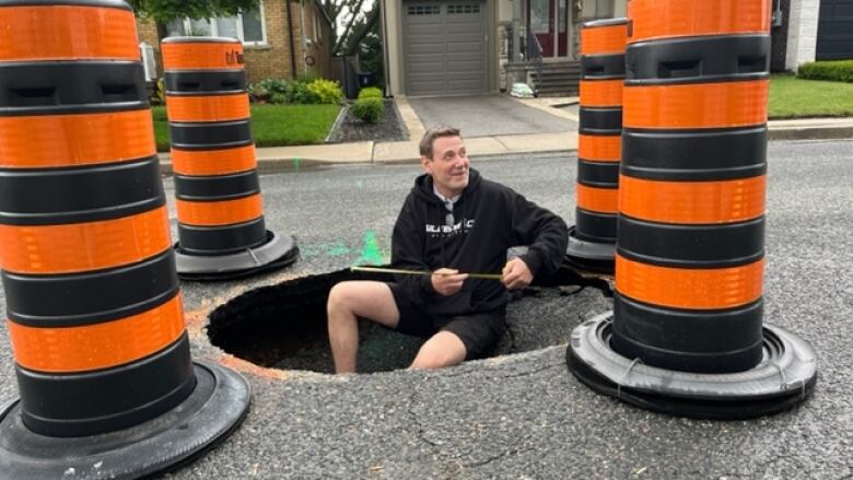 Murray Clark, of Glen Albert Drive, measures the sinkhole that opened up in front of his East York home two months ago. 