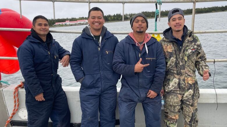 four men stand together on a boat.