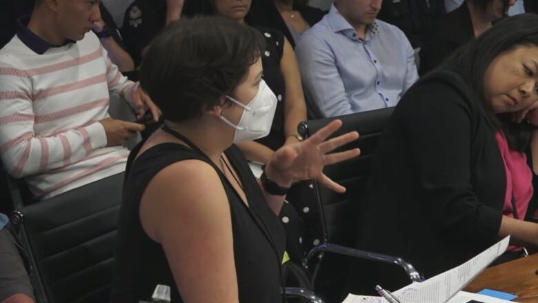 A white woman with short brown hair sits at a board room table.