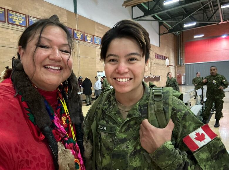 An older and younger woman stand together smiling.