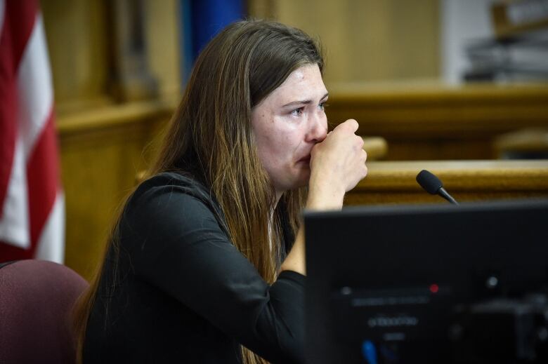 A young woman testifies with tears in her eyes