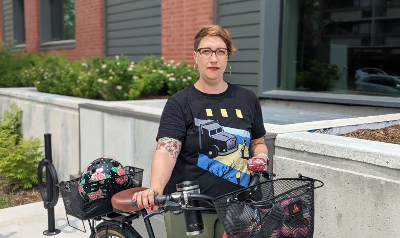 A woman poses for a photograph with a bike.