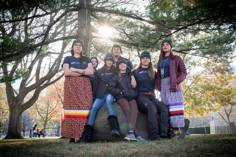 the group of seven young people stand in a park