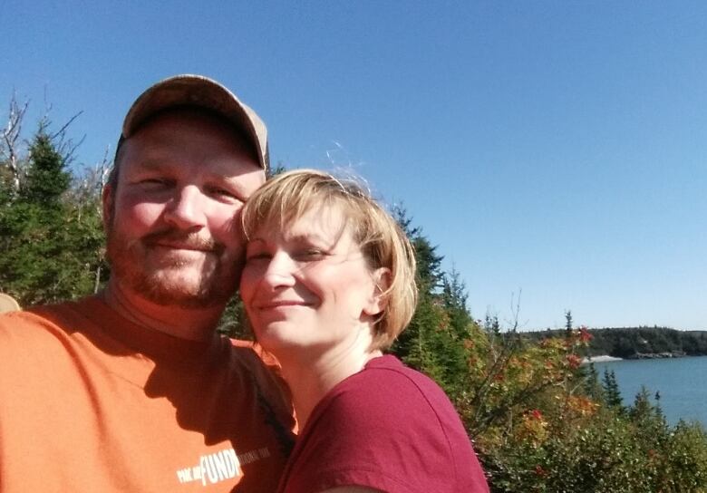 A couple pose for a picture overlooking a scenic view of the ocean.