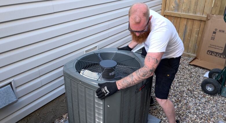 Danny North moves a new air conditioner unit in place next to a home in northwest Calgary. 