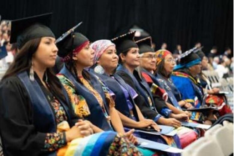 People sit together, with some of them in black gowns.