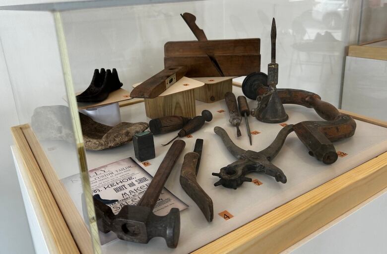 A glass case holding old farm tools. 