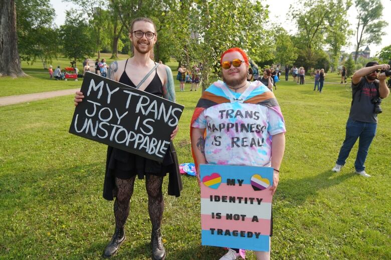 Two pride march attendees are holding signs saying 