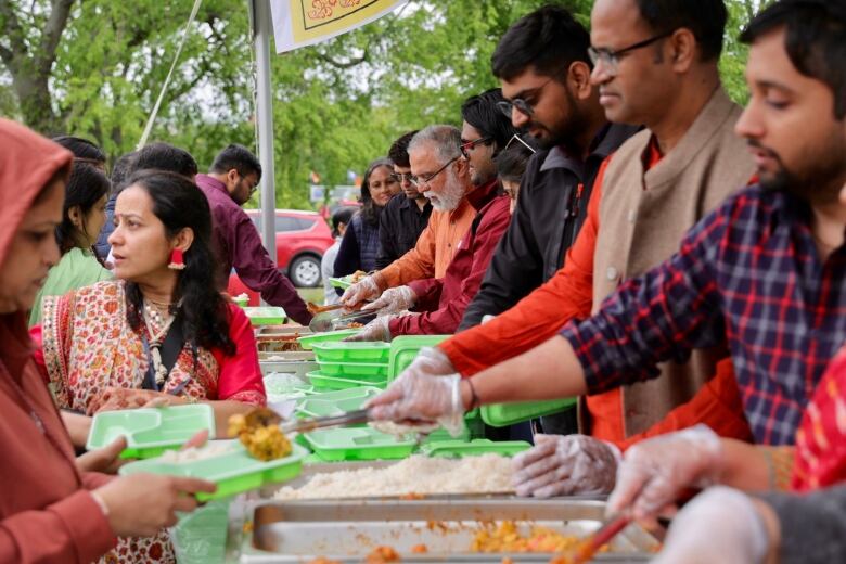 People scoop out curries into takeout containers