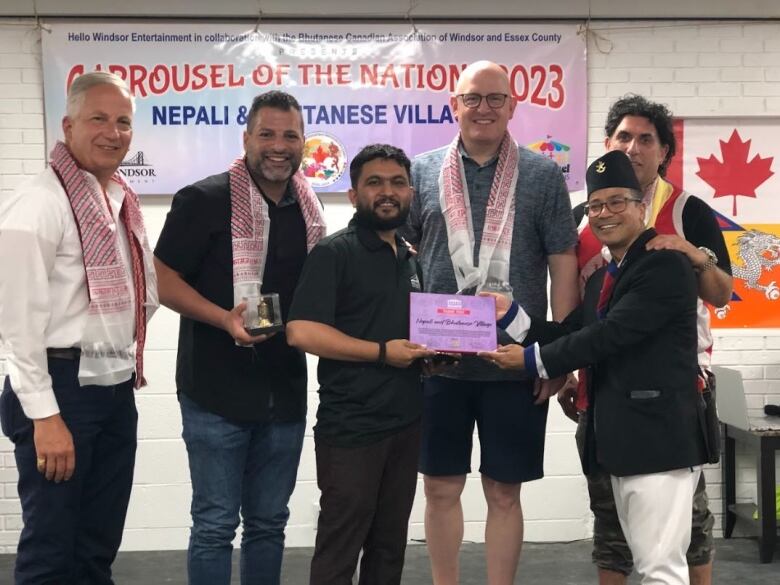 Six men posing for a photo, with two of them holding a plaque