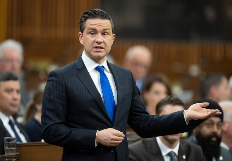 A politician gestures to his left while speaking in a legislature.