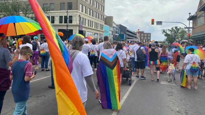 A large crowd of supporters march in the 2023 pride parade. Many are carrying rainbow flags, umbrellas and clothing.