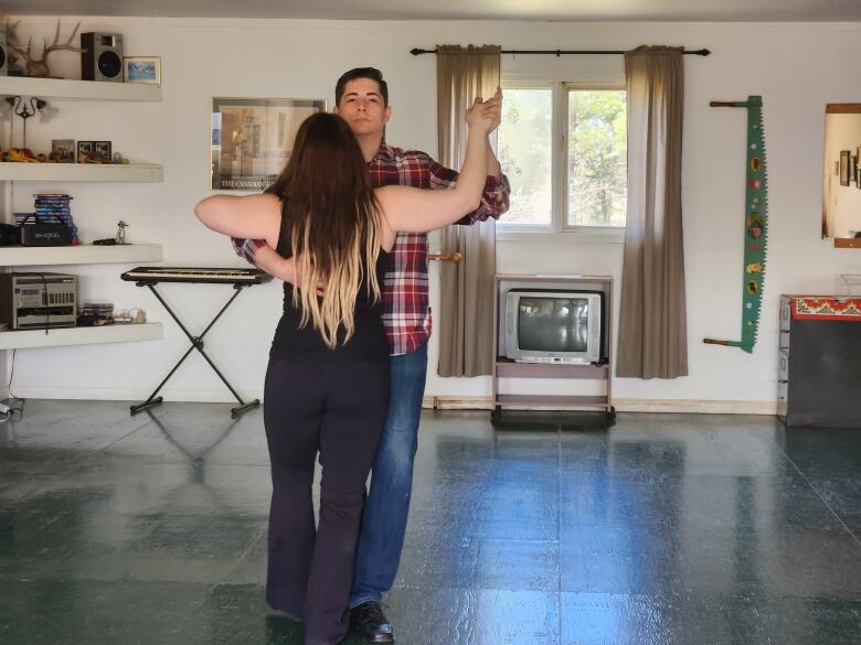 A couple dances closely in a room with green floors.