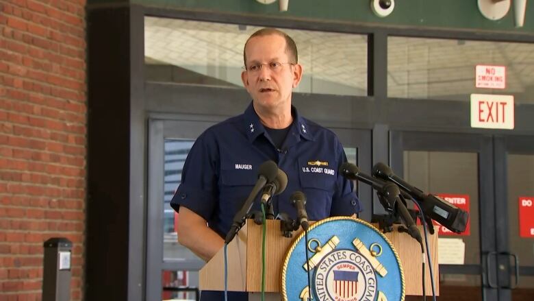 A man wearing a U.S. Coast Guard uniform stands at a podium.