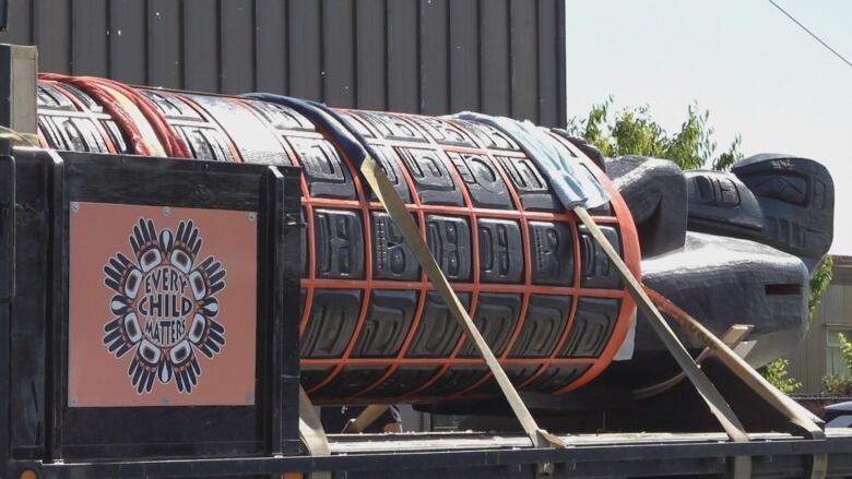 Giant black and orange totem pole on the back of a flatbed truck ready to be transported to Vancouver for National Indigenous Peoples Day. 