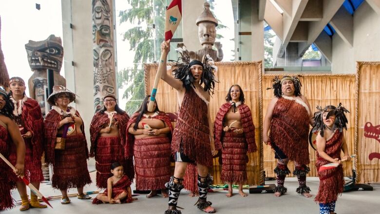 A group of Indigenous dancers and singers performing in traditional attire at UBC's Museum of Anthropology.