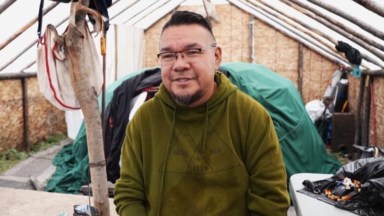 A man in a green sweater sits in a chair. 